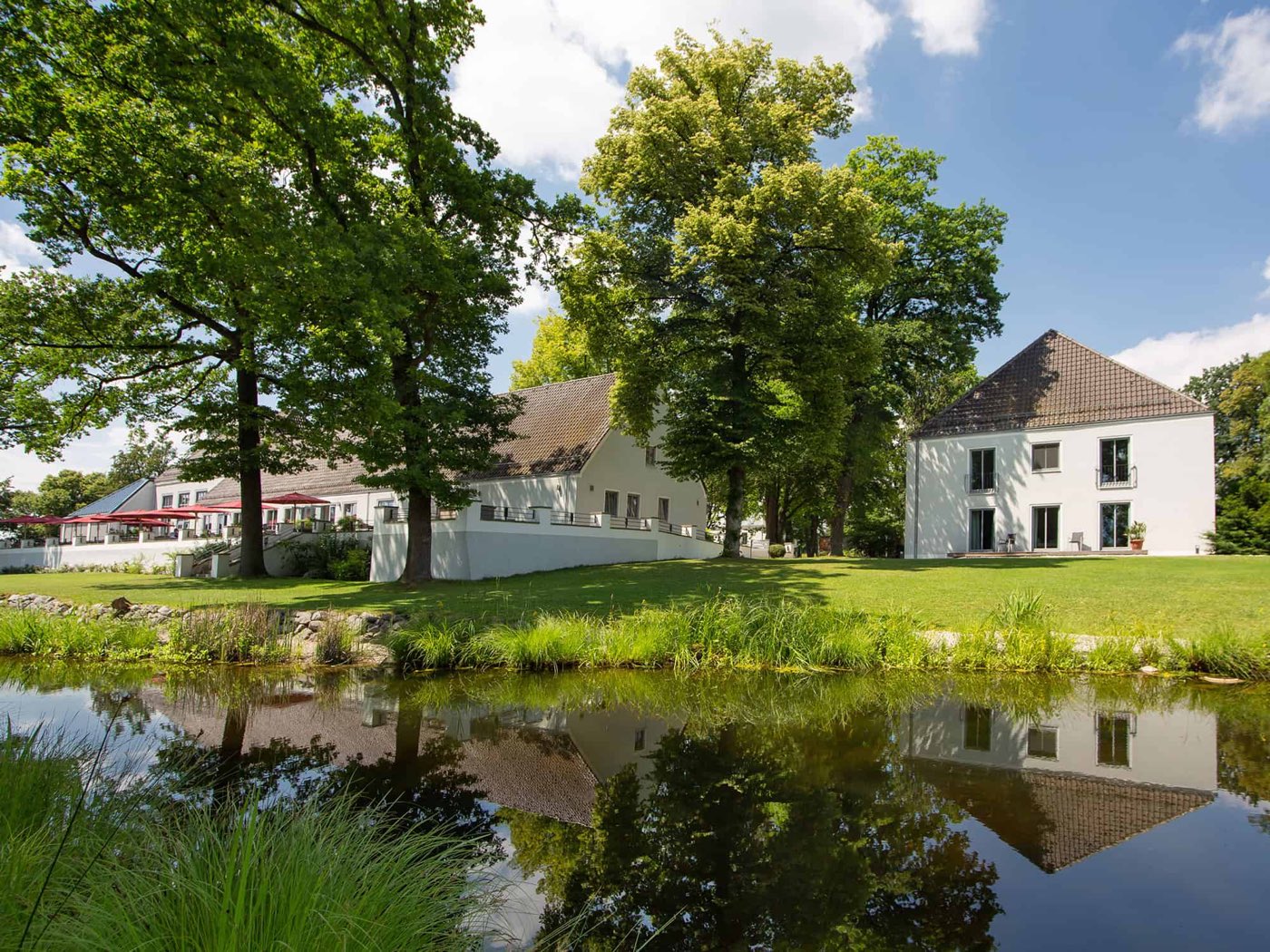 Außenansicht des Parkhotels mit Teich und altem Baumbestand
